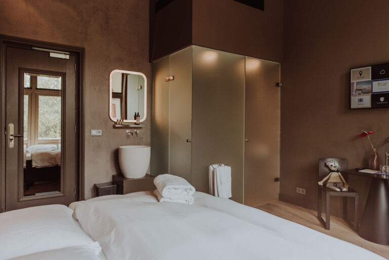 A cosy Hotel Blue room with a warm interior, a white bed and art on the walls